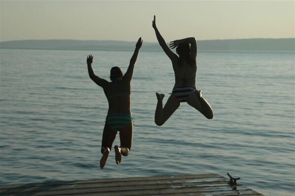 Two people jumping off a dock into a body of water. - Madeline Island Cottage Overlooking Apostle Islands (LaPointe)