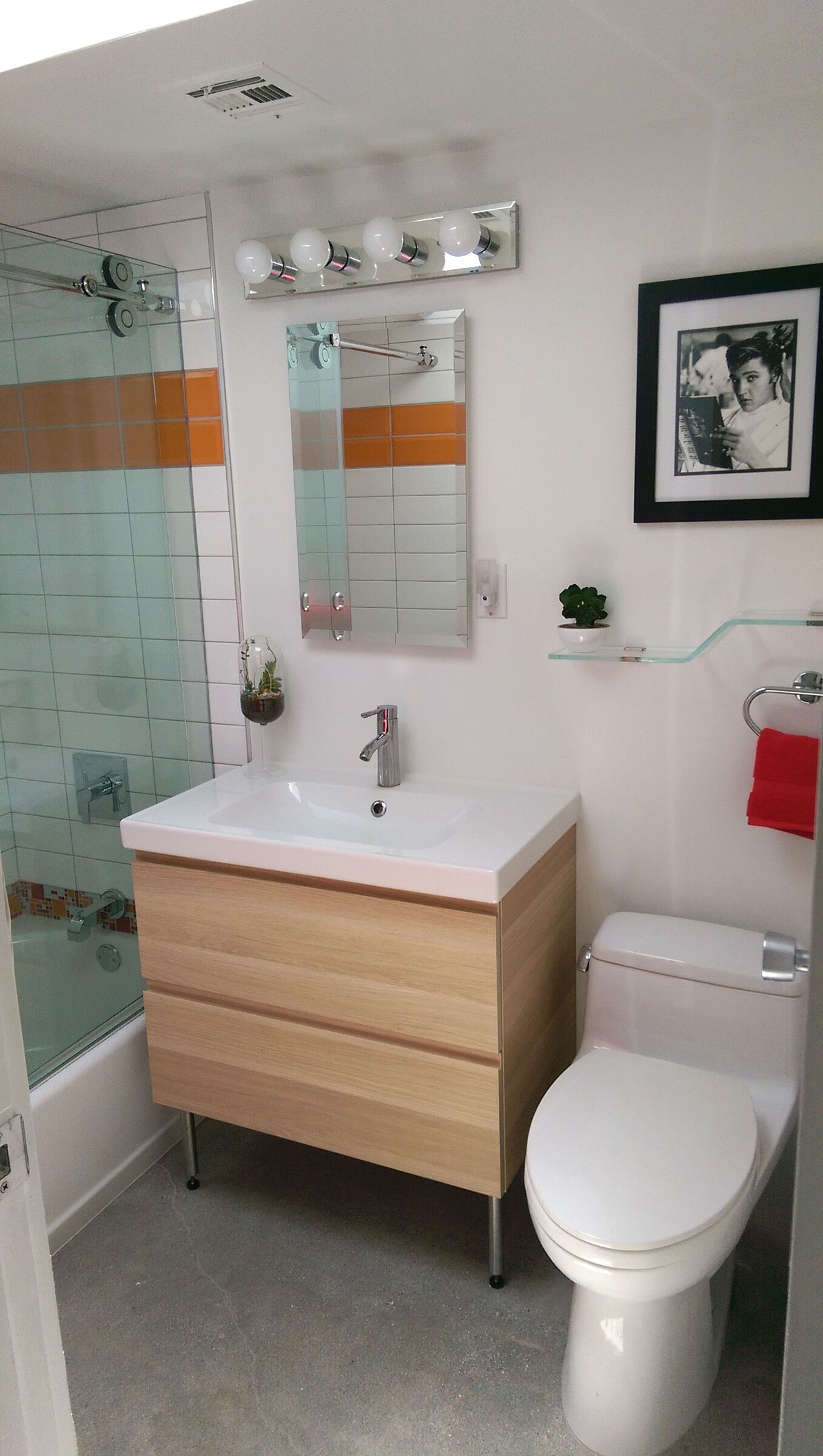 A bathroom with a white sink, wooden vanity, glass shower enclosure, and a toilet.