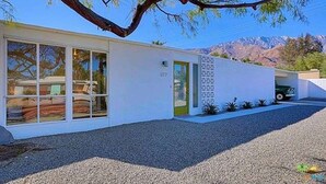 A modern building with large windows, a green door, and a gravel driveway. - A Mid-Century Modern Alexander Home Oasis (Lively Music-Themed Decor). (Palm Springs)