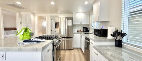 Una cocina moderna con armarios blancos, electrodomésticos de acero inoxidable y encimera de mármol.