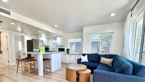 A modern kitchen with white cabinets, a central island, and wooden stools. - NEW July 2026 Remodel! Triton`s Castle Overlooking Beach and Bay! (San Diego)