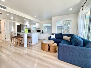 A modern kitchen with white cabinets, a central island, and wooden stools. - NEW July 2026 Remodel! Triton`s Castle Overlooking Beach and Bay! (San Diego)