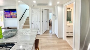 A modern kitchen with a marble countertop, a built-in stove, and a dining area with a bench.