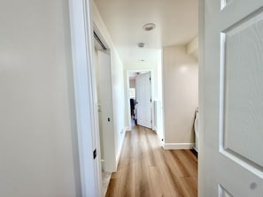 A hallway with wooden flooring, white walls, and a door leading to a room. - NEW July 2026 Remodel! Triton`s Castle Overlooking Beach and Bay! (San Diego)