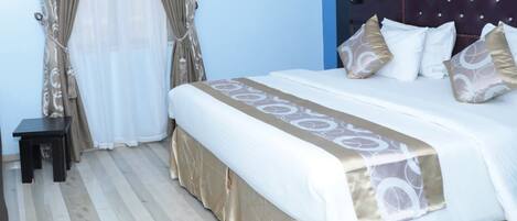 A neatly made bed with a patterned bedspread and pillows, a bedside table, and a headboard with a lamp.