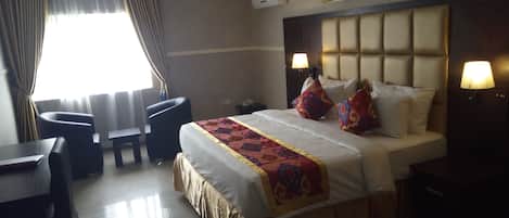 A hotel room with a bed, bedside lamps, a desk, and a chair.