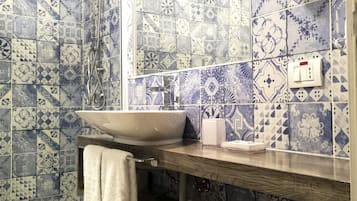 Een badkamer met patroon betegelde vloer, een wastafel, een handdoekhouder en een douche.