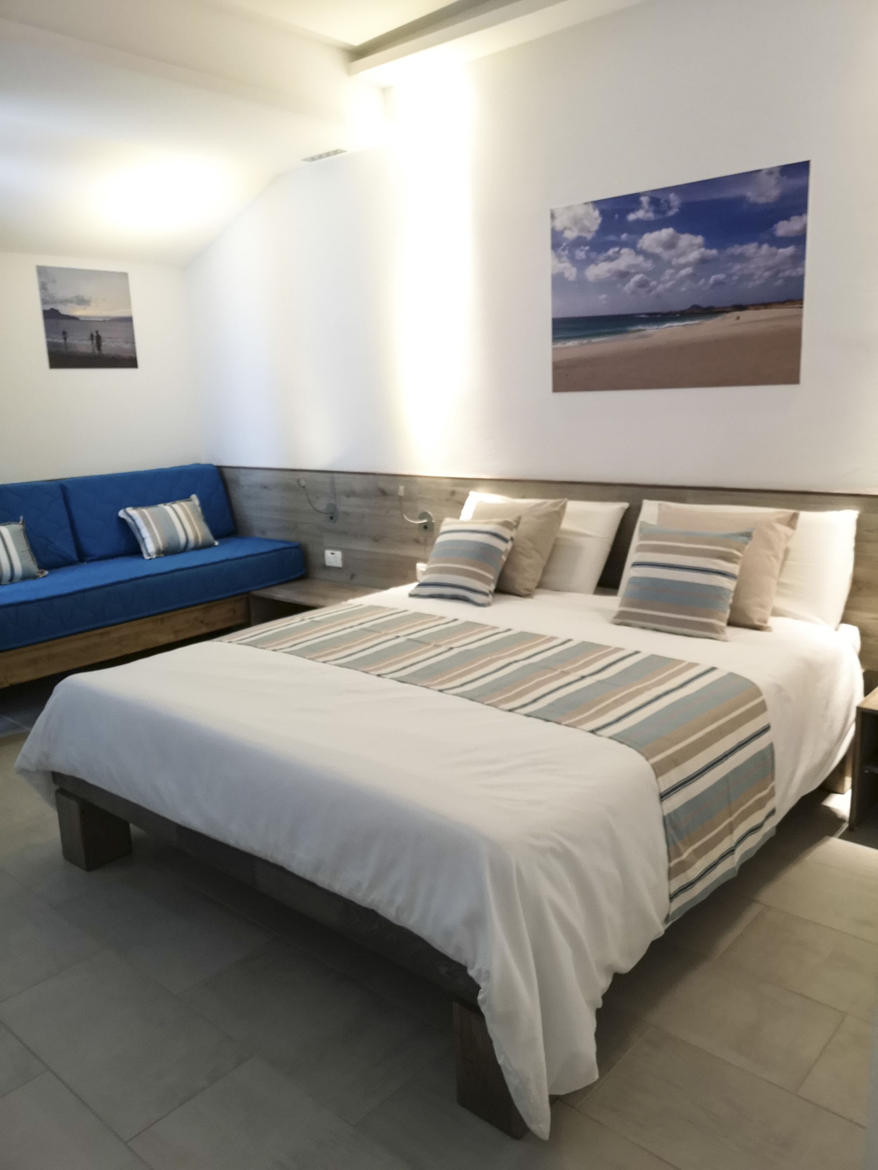 Une chambre à coucher avec un lit, un canapé bleu et deux œuvres d’art murales.