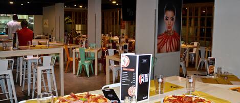 A restaurant with tables, chairs, and pizza.