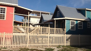 Une maison à deux étages avec une terrasse en bois et une clôture faite de piquets.