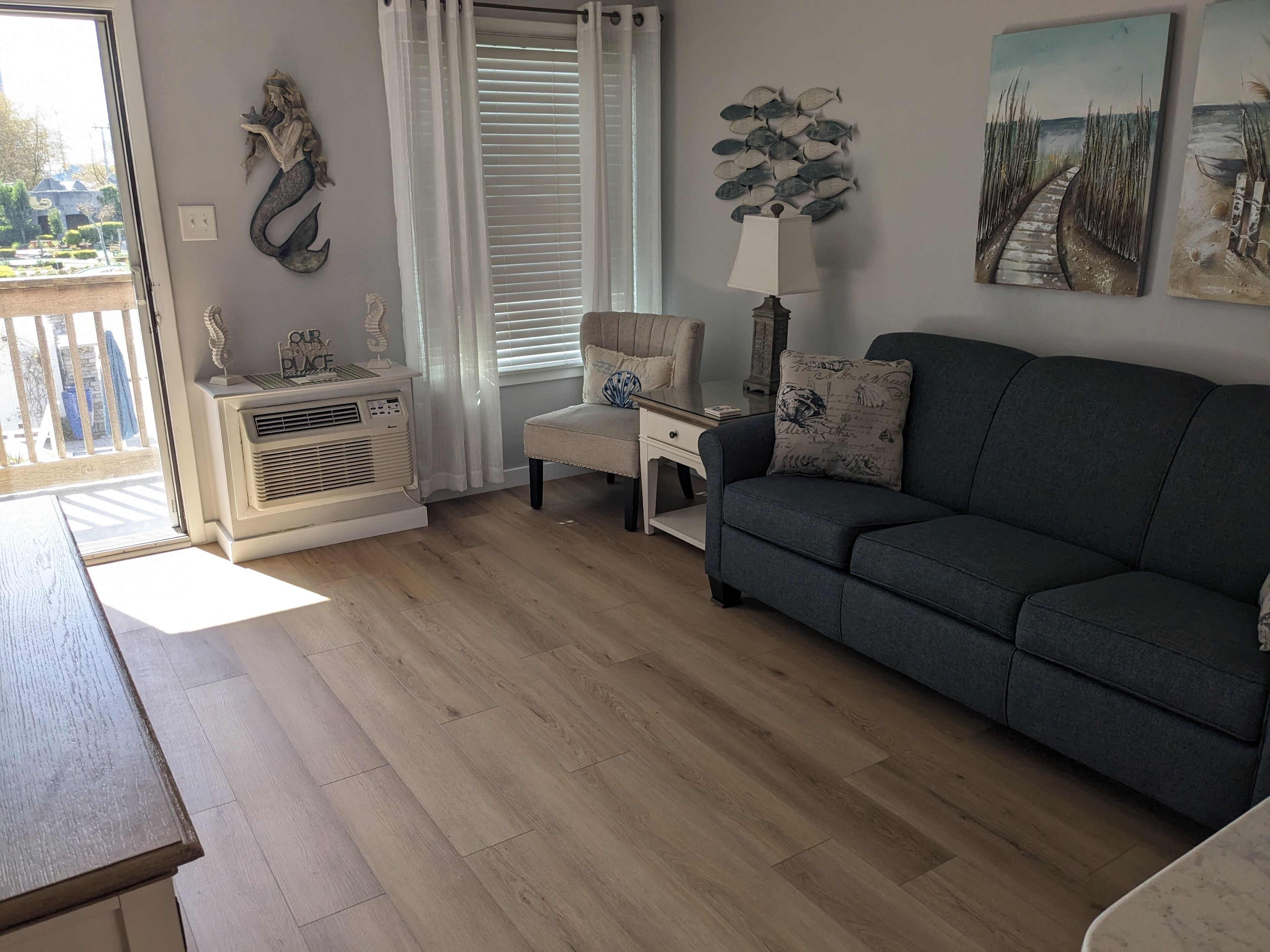 Un salon comprenant un canapé, un fauteuil, une table et une décoration murale représentant des poissons.