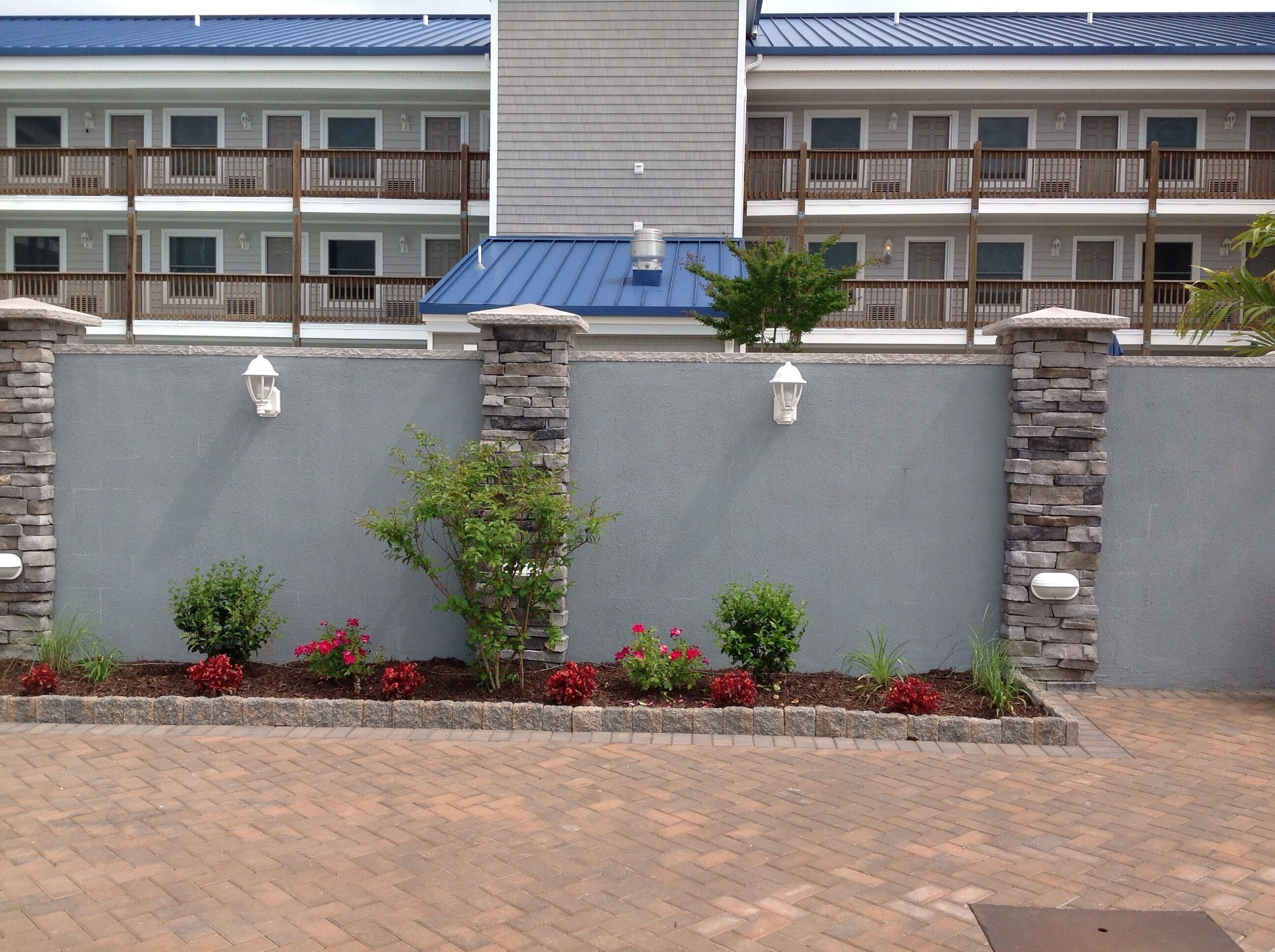 A hotel with a grey exterior, stone pillars, and a brick-paved entrance.