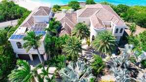 A coastal property with multiple buildings, solar panels, and lush greenery.