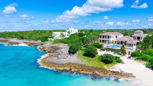 A coastal property with multiple buildings, a beach, and rocky shoreline.