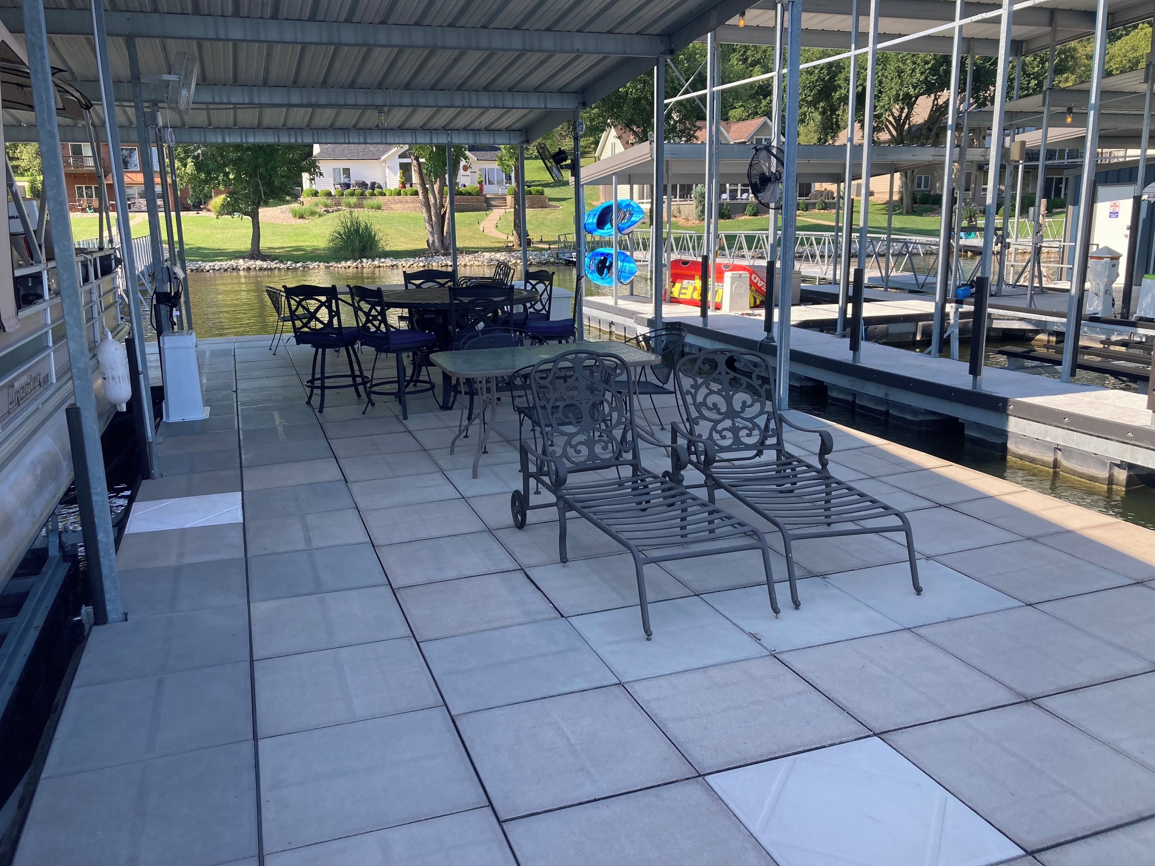 Een overdekt terras met betegelde vloer, metalen stoelen en tafels.