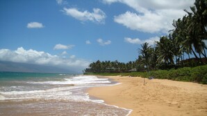A beach with clear skies, palm trees, and a sandy shore. - Just Steps to Kamaole III Beach!!! (Kihei, Maui)