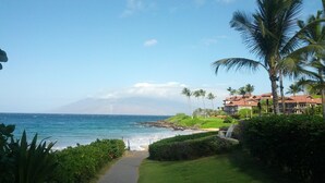 A pathway leading to a beach with a view of the ocean and a mountain in the distance. - Just Steps to Kamaole III Beach!!! (Kihei, Maui)