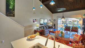 A modern kitchen with a large island, a dining area with chairs, and a living room with a sofa and a coffee table. - Just Steps to Kamaole III Beach!!! (Kihei, Maui)