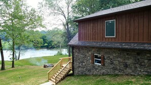 Un bâtiment en pierre doté d’une terrasse en bois et offrant une vue sur une rivière.