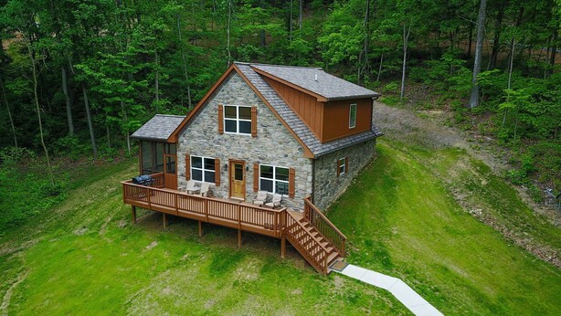 Une cabane en pierre dotée d’une terrasse en bois et d’un escalier menant à un deuxième niveau.