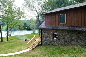 Overlooking a serene river, this cabin offers a peaceful retreat surrounded by lush greenery and a cozy outdoor space with a fire pit.