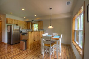 Kitchen area with a refrigerator, trash bin, and dining table with chairs.