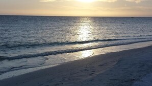 Een strand met een rustige zee en heldere lucht.