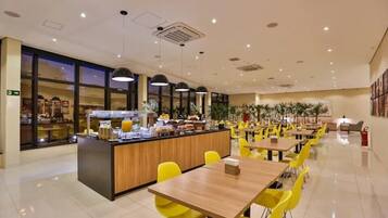 Um restaurante moderno com balcão central, cadeiras amarelas e mesas.