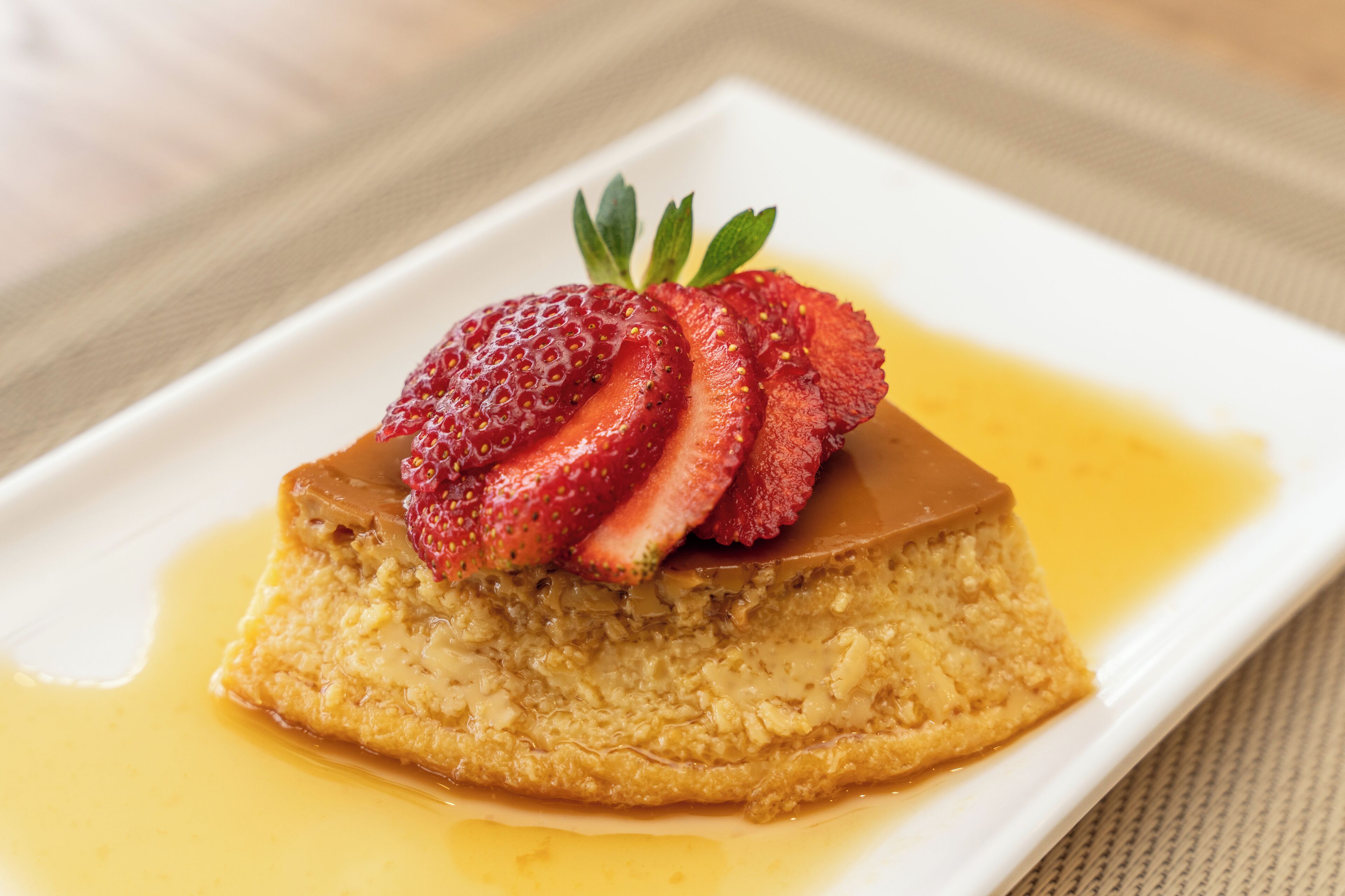 A dessert with strawberries and caramel on a white plate.