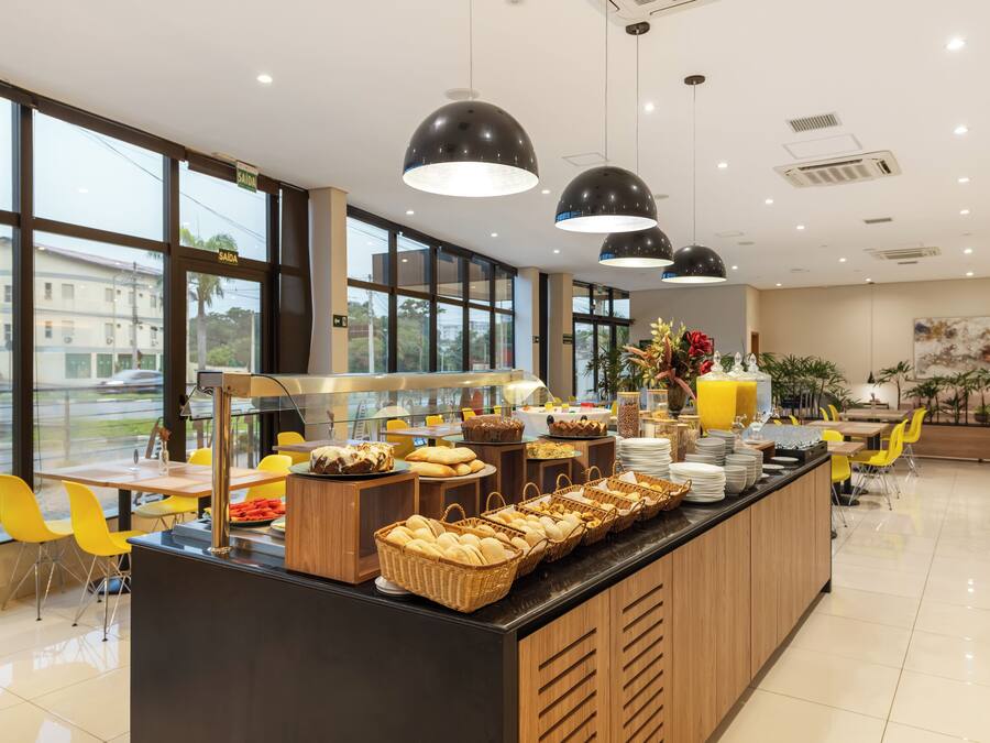 Et moderne morgenmadsområde med buffet, store vinduer og gule stole.