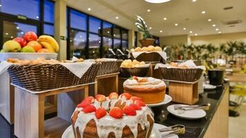 A buffet with various baked goods and fruits.