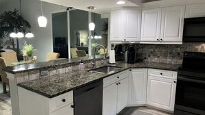 A modern kitchen with white cabinets, granite countertops, a built-in dishwasher, a stove, and pendant lighting. - Gated Community/Lazy River/Pool/Tennis/Granite/Tile/Lanai with Kitchen (Naples)
