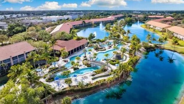 An aerial view of a resort with multiple swimming pools, palm trees, and a large body of water. - Gated Community/Lazy River/Pool/Tennis/Granite/Tile/Lanai with Kitchen (Naples)