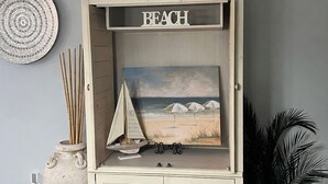 A wooden cabinet with a beach-themed painting, a potted plant, and a decorative sign. - Gated Community/Lazy River/Pool/Tennis/Granite/Tile/Lanai with Kitchen (Naples)