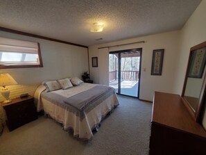 A bedroom with a bed, a nightstand, a lamp, a sliding glass door to a balcony, and framed artwork on the walls. - Sparky's-Lakefront, Beautiful Shoreline- Close to Swim Pool & Marina! (Garfield)