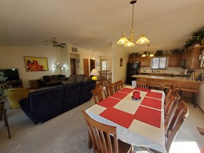 A dining area with a table set for four, a sofa, and a ceiling fan.