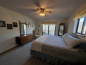 A bedroom with a bed, dresser, chair, and a ceiling fan.