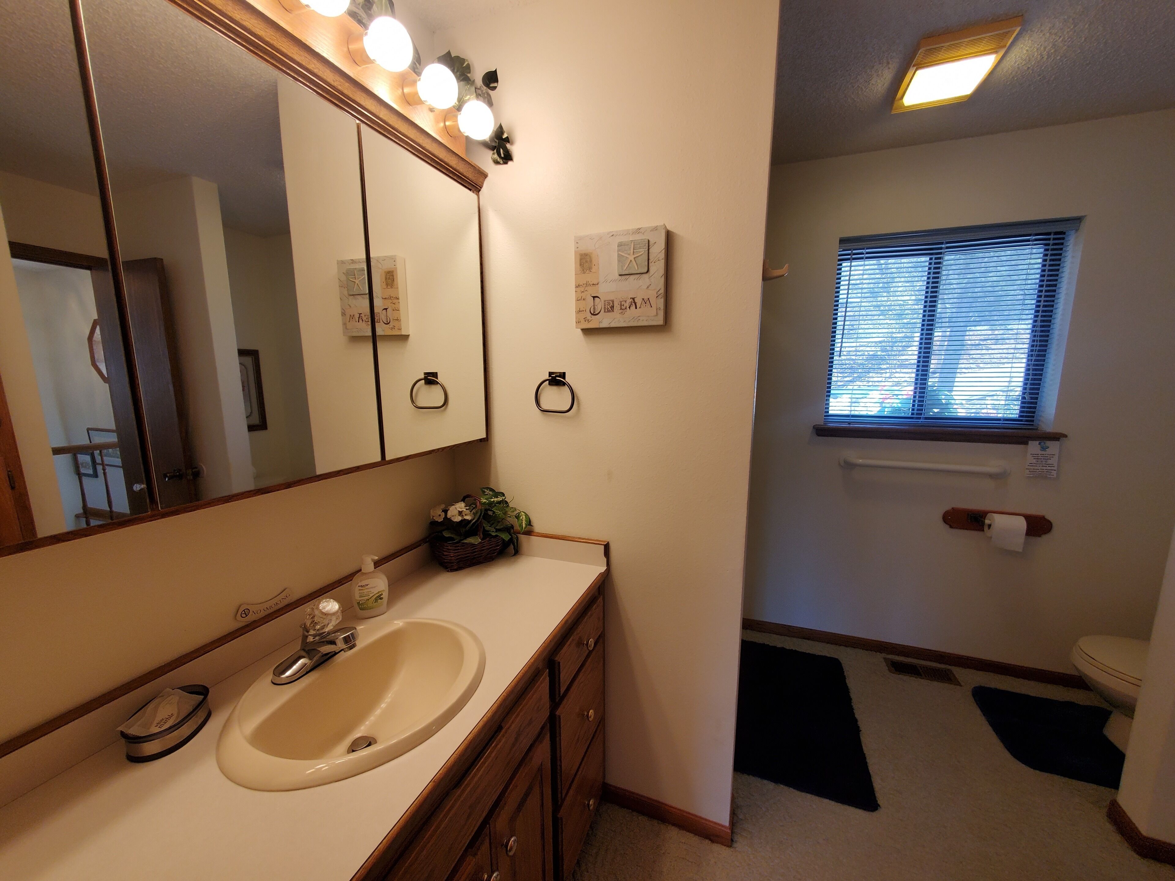 Une salle de bain avec un lavabo, un miroir et une fenêtre.