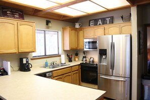 A kitchen with wooden cabinets, a stainless steel refrigerator, a microwave, and a dishwasher. - Stunning Alpine Retreat in South Lake Tahoe! (South Lake Tahoe)