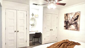A bedroom with a bed, a desk, a chair, and a ceiling fan.