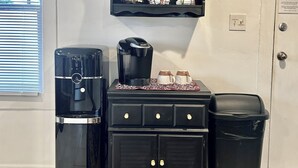 A kitchenette with a coffee maker, a small cabinet, and a trash bin.