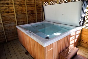 A hot tub with a wooden exterior and a white interior, surrounded by wooden walls and a wooden deck. - Mountaineer Cabin 3 - Hot Tub & Fireplace close to New River Gorge National Park (Hico)