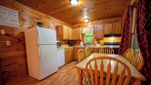 A wooden cabin kitchen with a refrigerator, stove, and wooden cabinets.