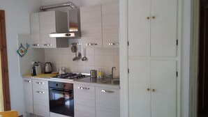 Une cuisine moderne avec des meubles blancs, une cuisinière à gaz, un four et des accessoires en acier inoxydable.