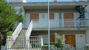 Un bâtiment à deux étages doté d’un balcon, d’un escalier en colimaçon et d’une porte.