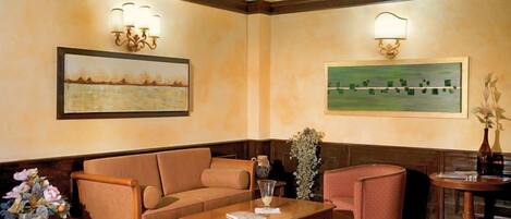 Un hall acogedor con un sofá, sillones, una mesa de centro y obras de arte en las paredes.