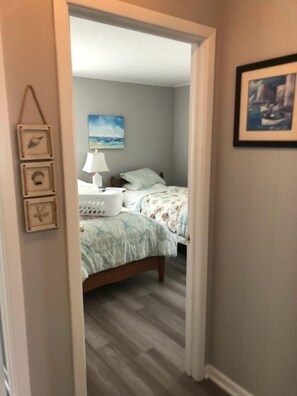 A bedroom with a bed, a nightstand, a lamp, and a painting on the wall.