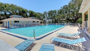 A swimming pool with lounge chairs and a building with a tiled roof.