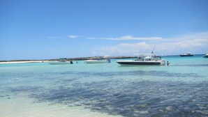 Een heldere turquoise zee met enkele boten afgemeerd bij de kust.