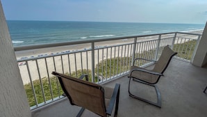 Un balcon avec deux chaises donnant sur une plage.